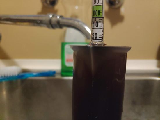 Hydrometer floating in beer in a reading cylinder, reading a value of 1.022