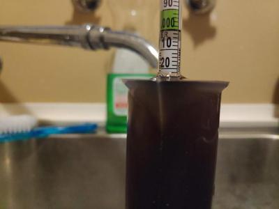 Hydrometer floating in beer in a reading cylinder, reading a value of 1.022